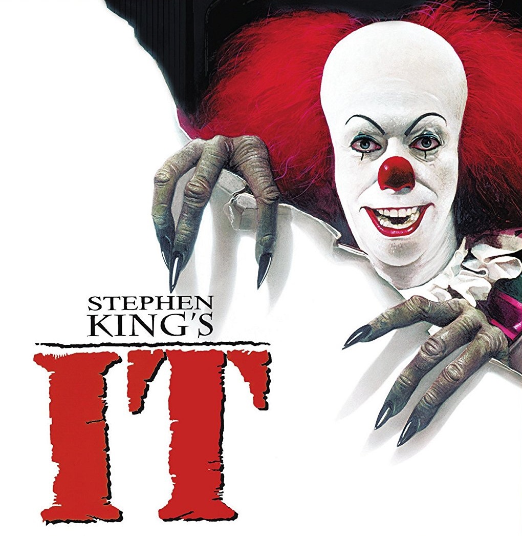 Cover art for Stephen King's "IT" features a sinister clown with pale skin, red hair, and sharp teeth, reaching forward with long, claw-like fingers. The bold red title "IT" instantly draws attention to the chilling presence of Pennywise.