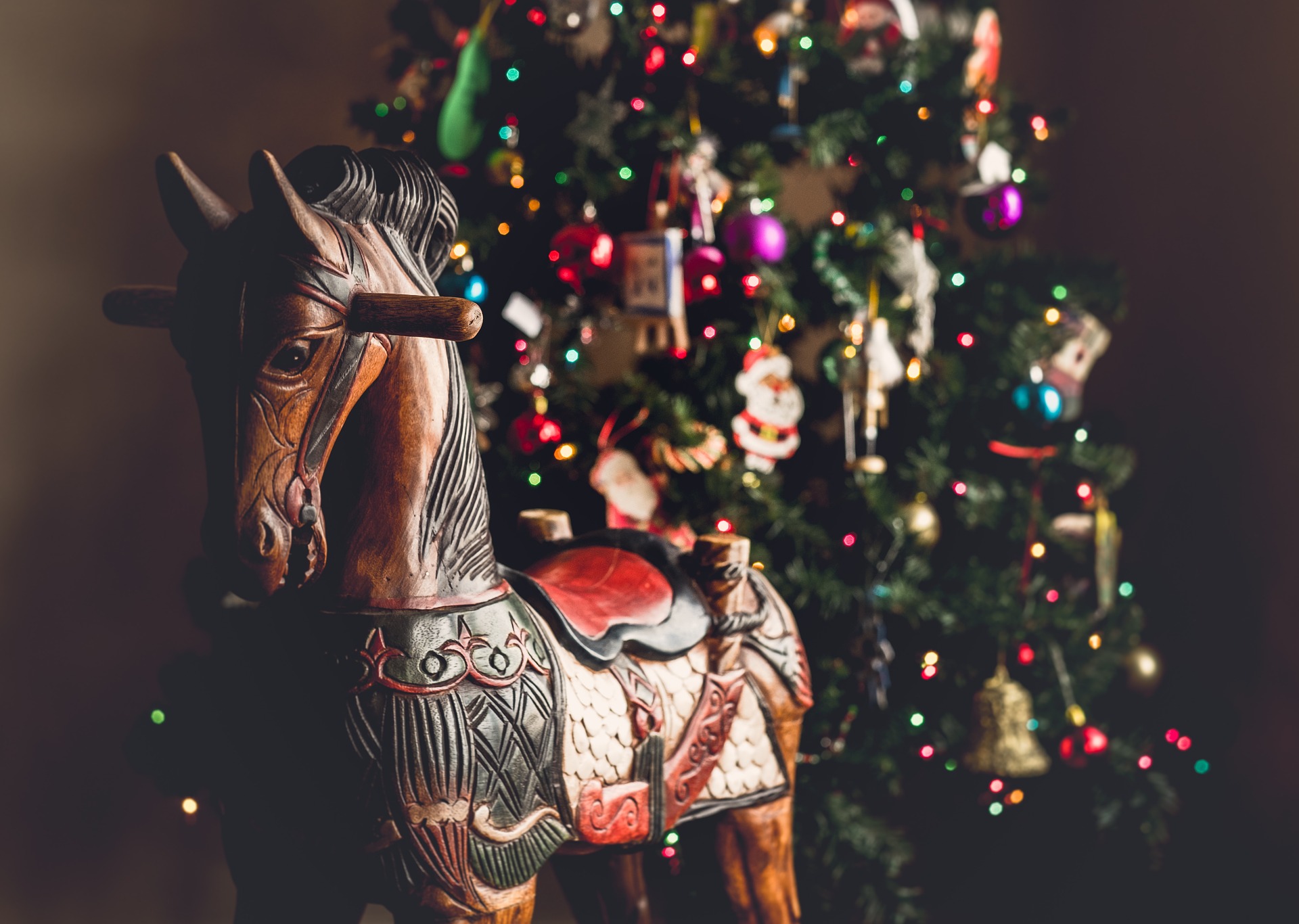 Wooden rocking horse in front of a decorated Christmas Tree