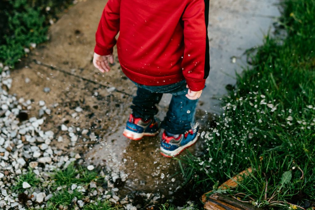 child jumping in a muddy puddle