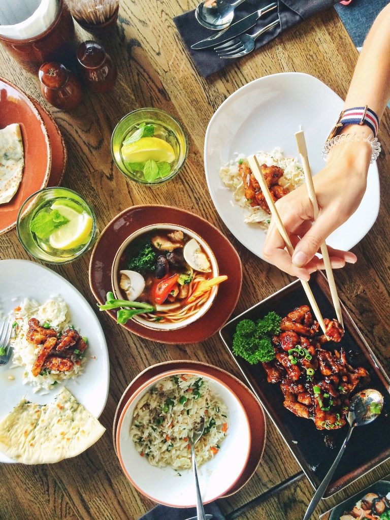 Chinese meal and person taking food from a bowl with chopsticks