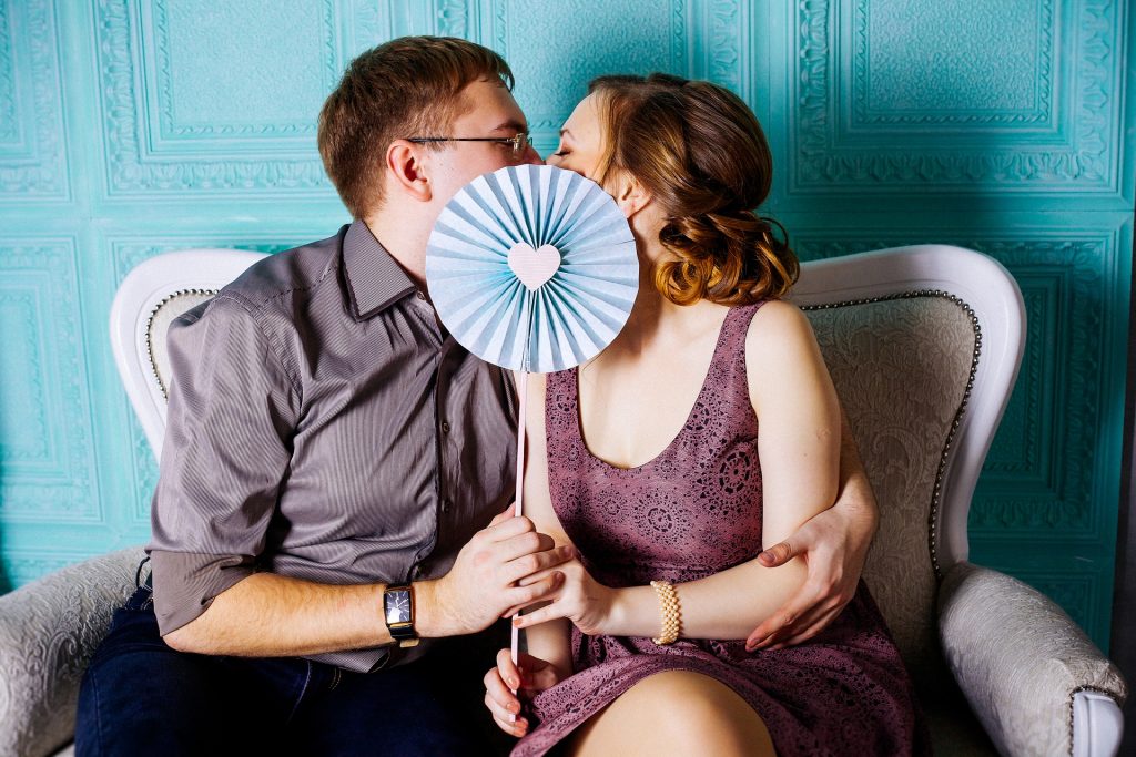 couple kissing behind a flower shaped fan