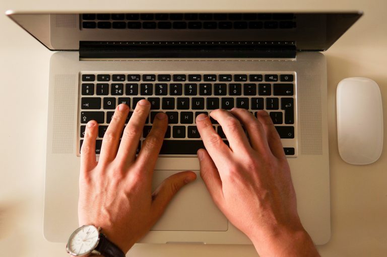 Ariel view of a man's hands typing on a laptop