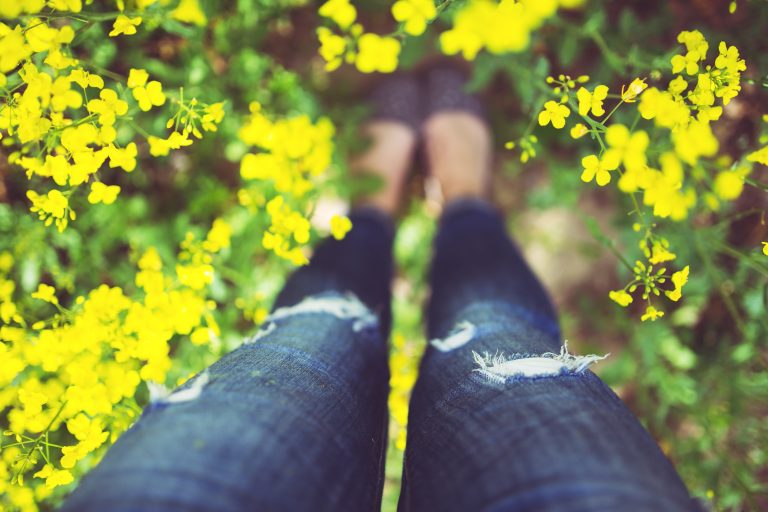 Woman standing in yellow blooming flowers - possibly in the spring