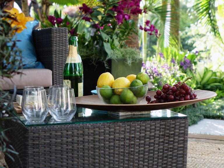 Rattan garden furniture, a sofa and table with a bottle of wine and fruit in a bowl