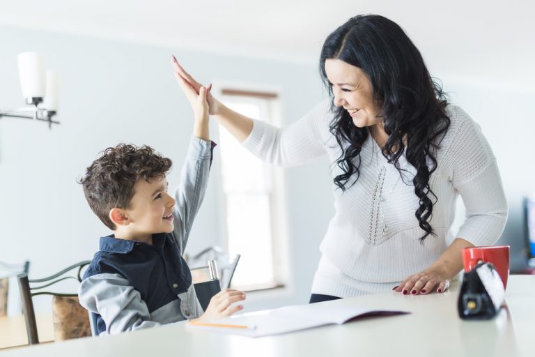 A mum helping her son with his homework - they are giving each other a high five