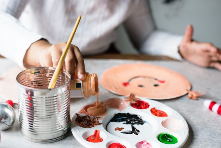 A child making a face from a paper plate and paints