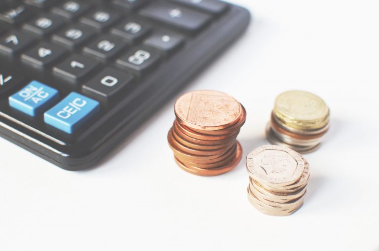 A black calculator and 3 piles of English money