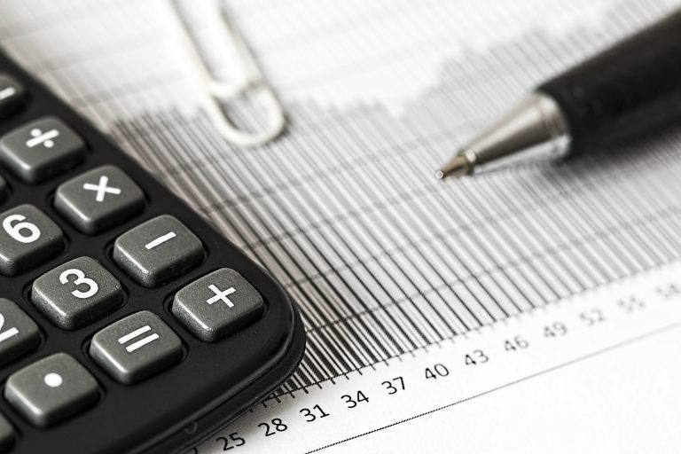 a calculator and pen sat on top of a spread sheet