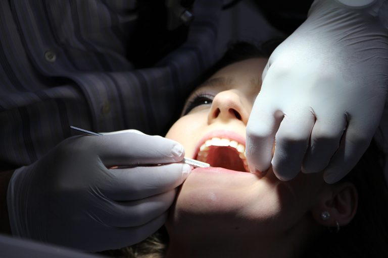 woman having her teeth checked by the dentist under a light