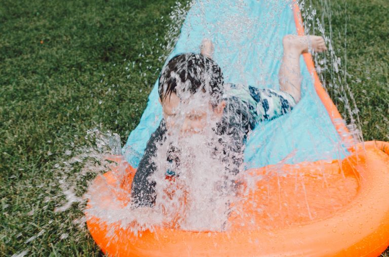 boy coming down a water slide in a garden