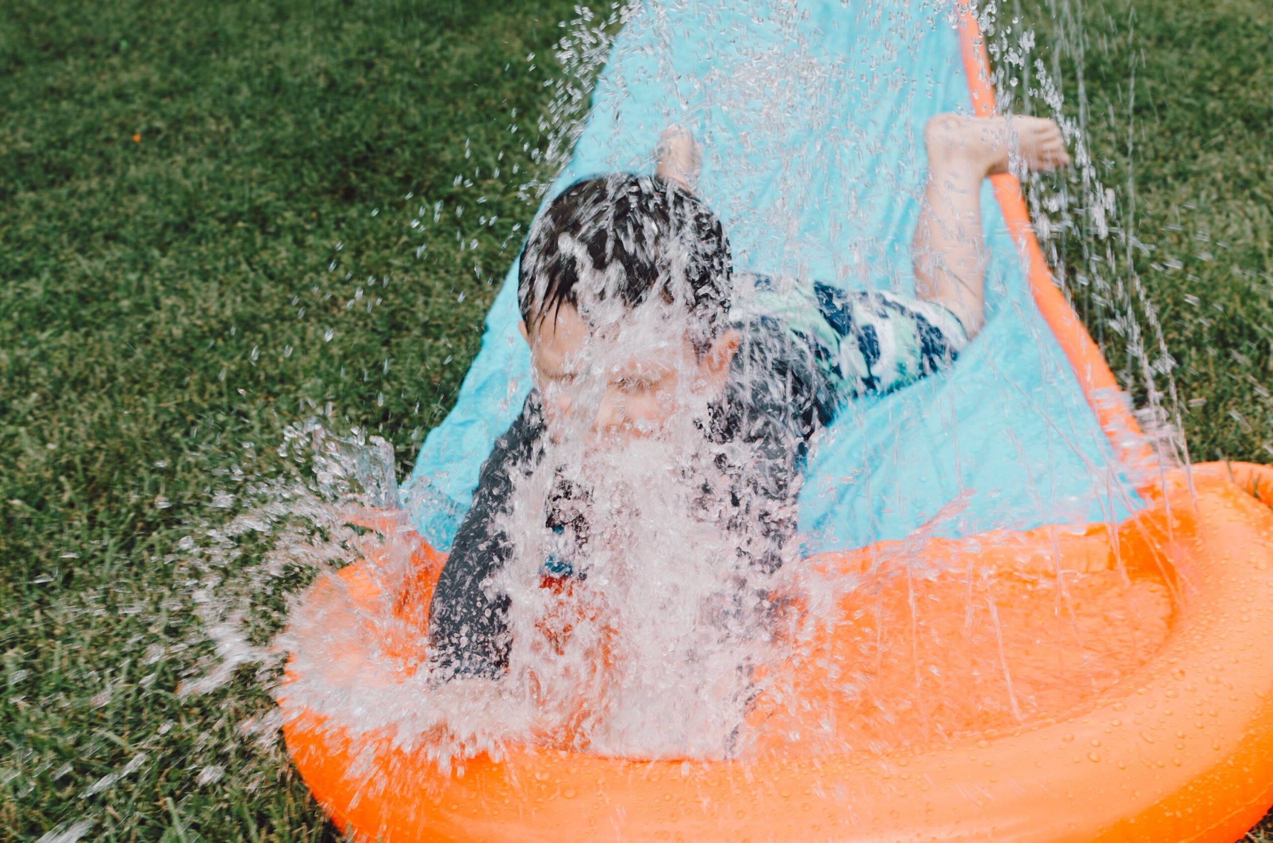 boy coming down a water slide in a garden
