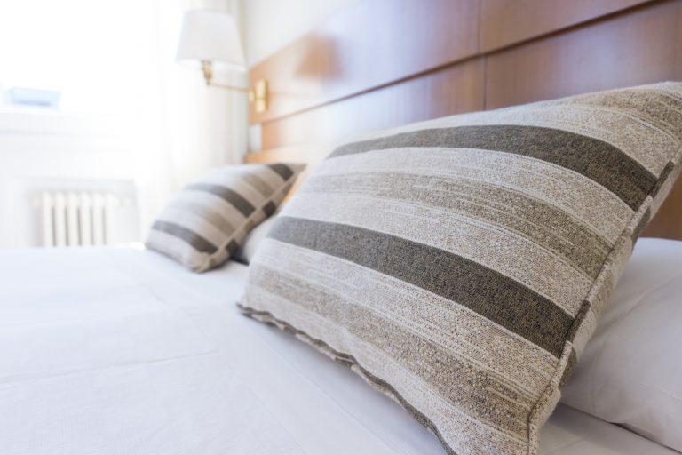two striped grey cushions sat on a king size bed in a hotel room