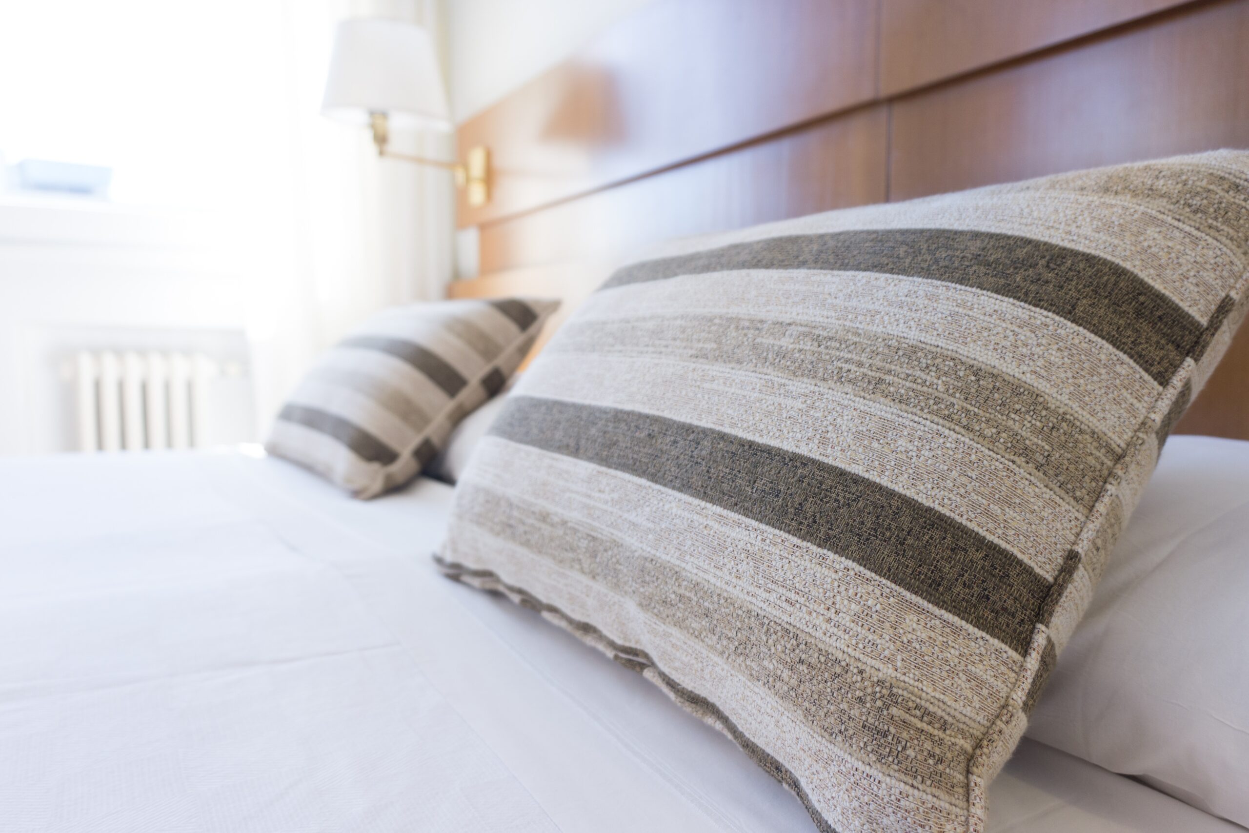 two striped grey cushions sat on a king size bed in a hotel room