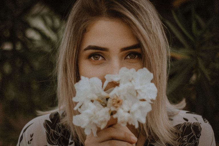 A woman with half her face hidden by a bunch of white flowers