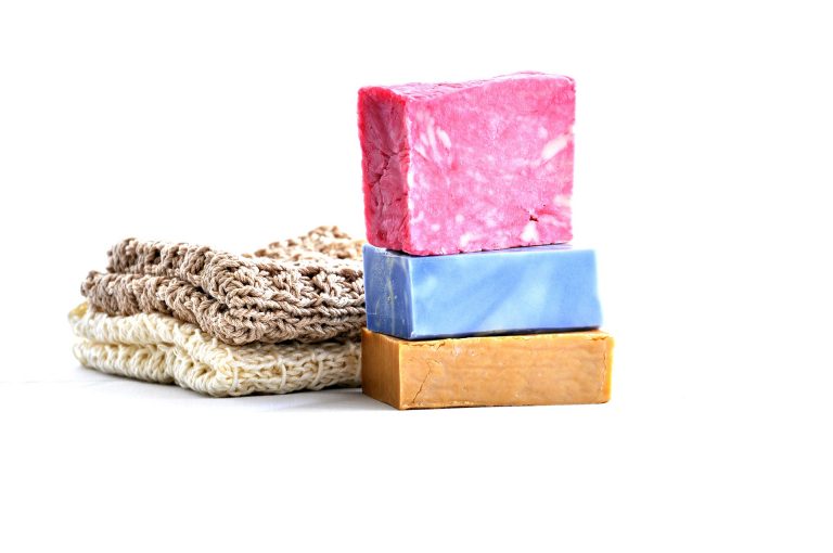 two bars of handmade soap next to two folded handmade garments