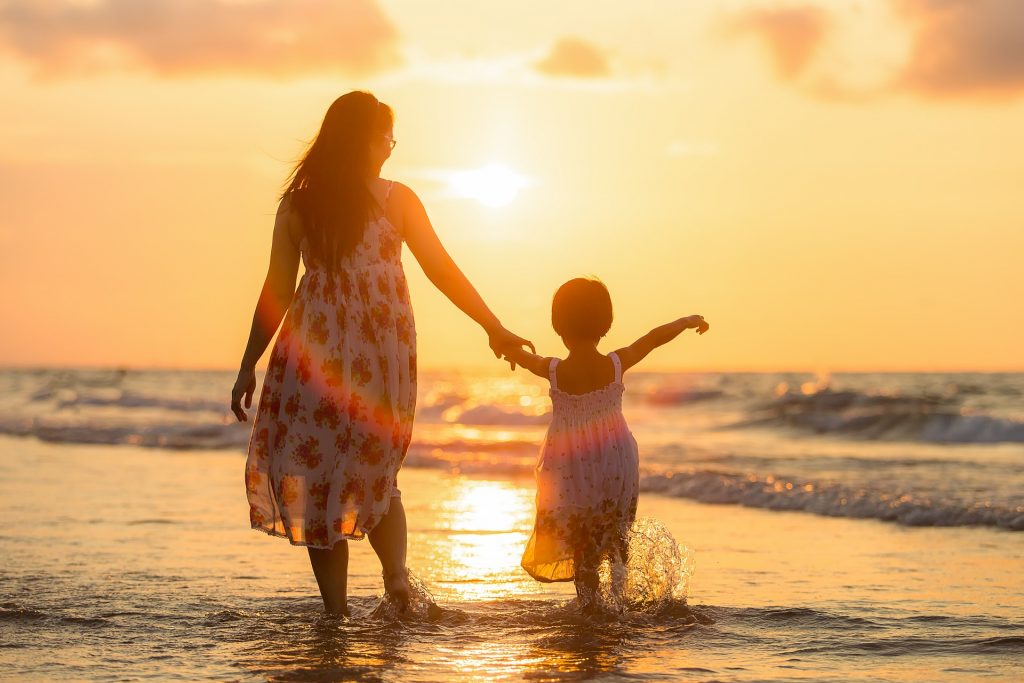 mother and daughter in the sea at sunset