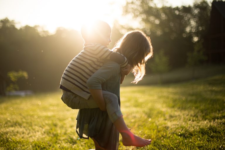 two children playing piggybacks in the garden in the summer