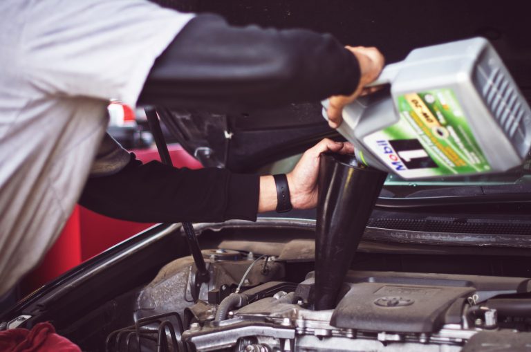 a man adding oil to a car engine