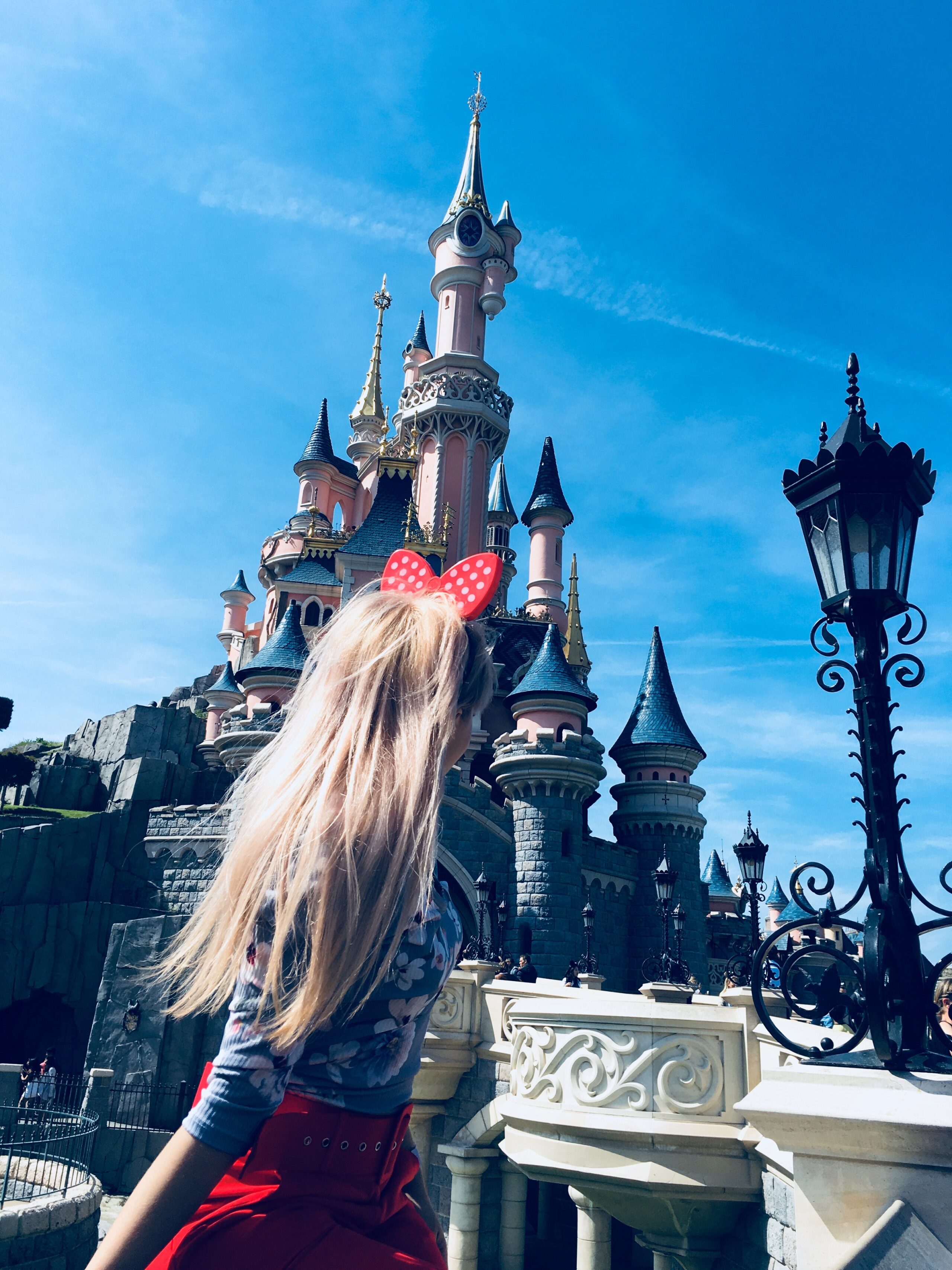 a girl with minnie mouse ears stood in front of the Disneyland castle
