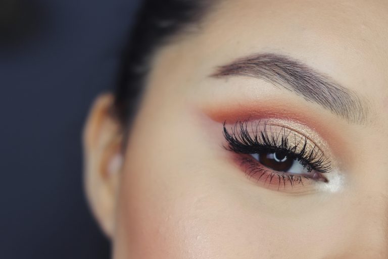 a woman's eye. she is wearing bronze eye shadow with a smokey effect