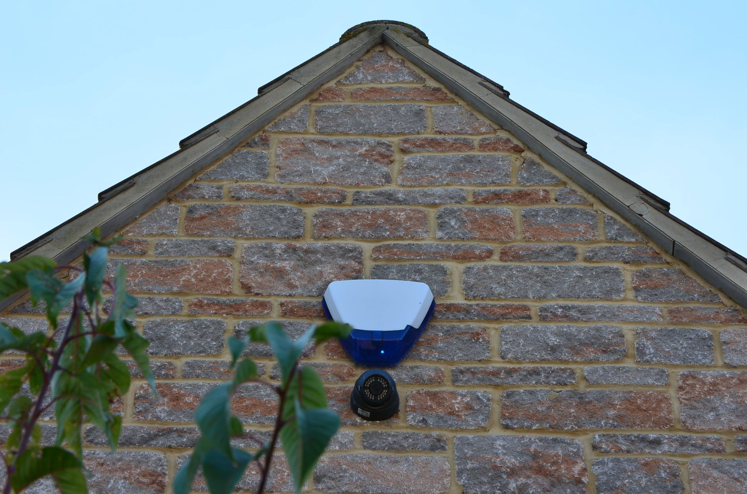 a security camera and a burglar alarm on the side of a house