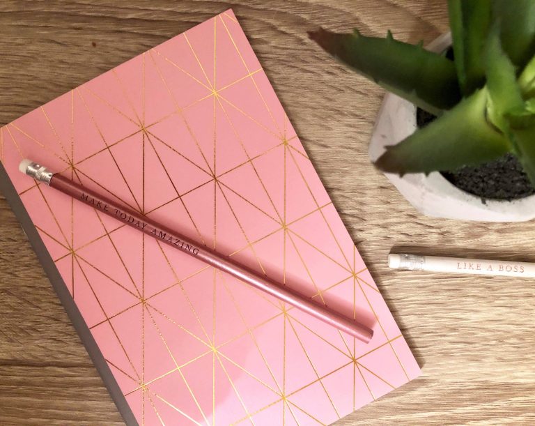 a pink pencil and pink notebook sat on a desk in an office