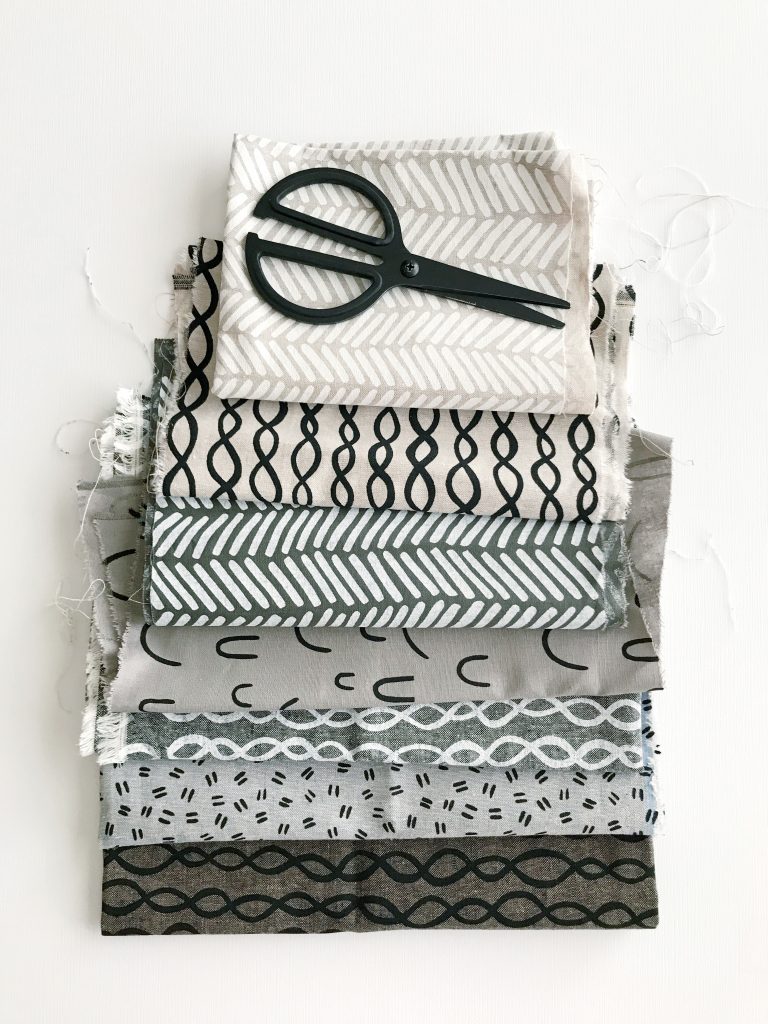 a pile of fabric samples with a pair of scissors sat on top
