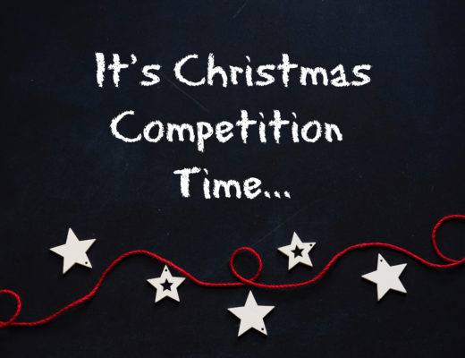 Blackboard with the text "It's Christmas Competition Time..." above a red string decorated with white star ornaments, inviting you to join the festive Christmas Cadbury competition.
