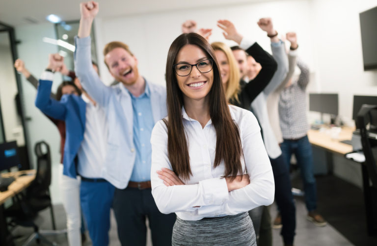 a group pf people cheering and a woman in front of them looking happy