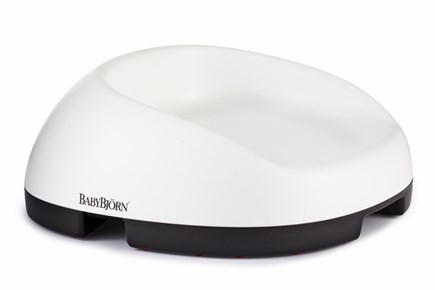 A white and black BABYBJÖRN booster seat designed for children, with a smooth, curved back and a low profile, shown on a plain white background.