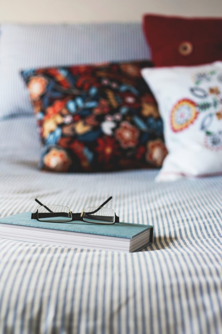 a book sat on a bed with a pair of glasses on top