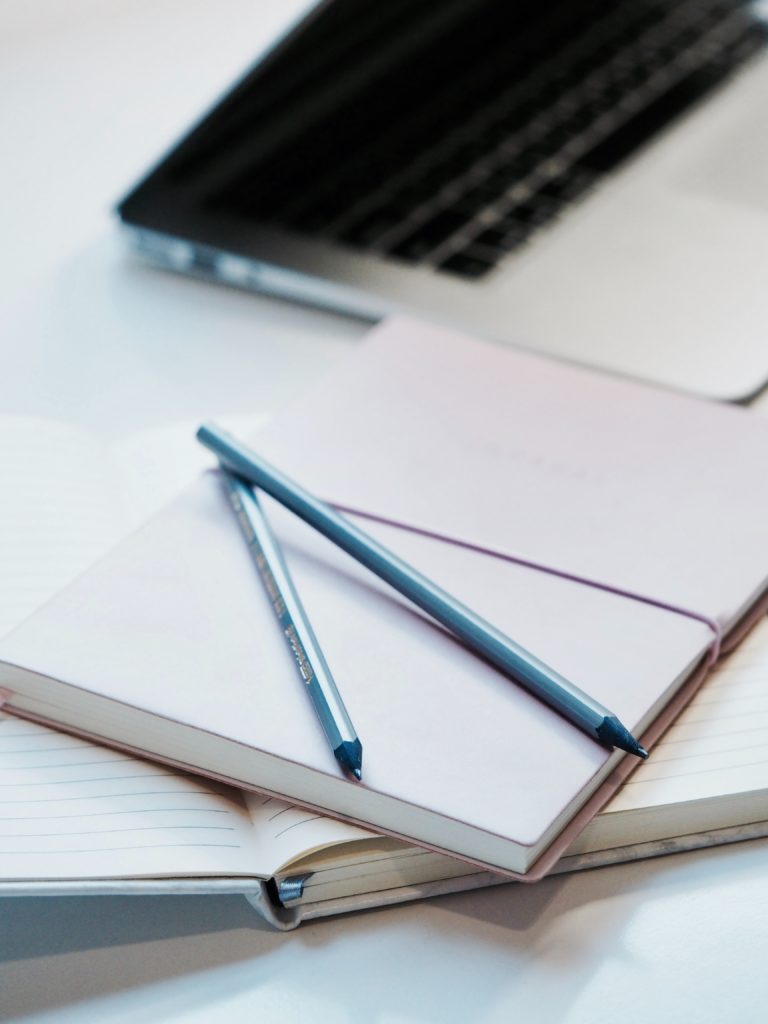 MacBook Pro with notebooks and pencils