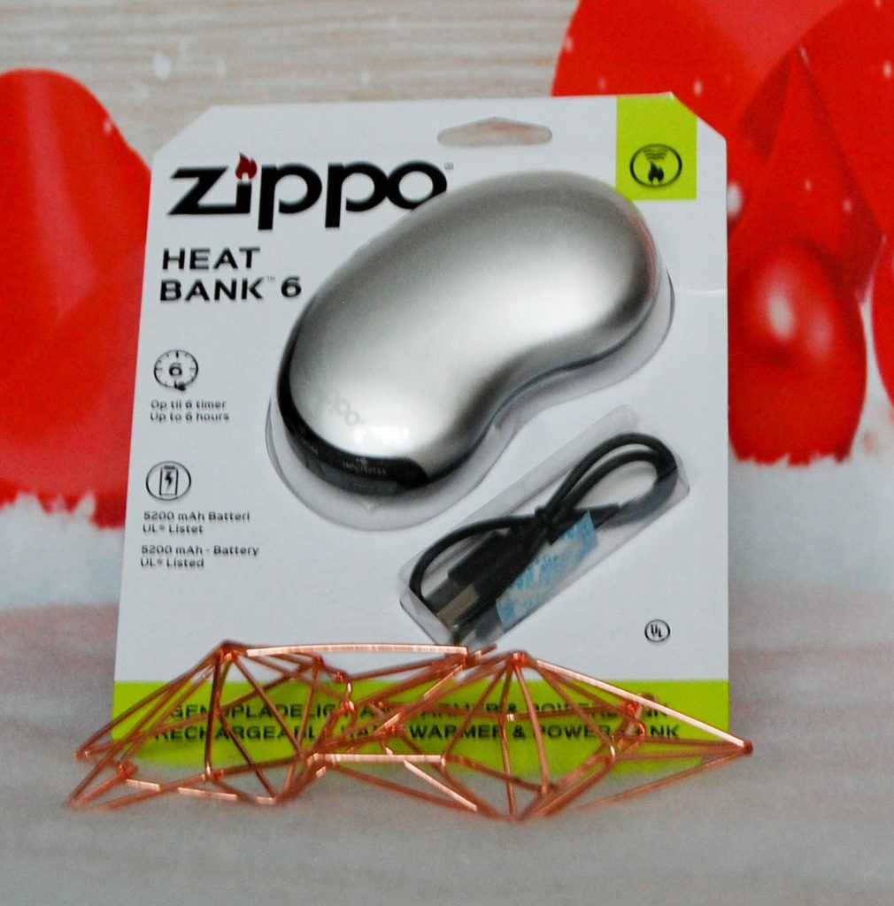 A Zippo HeatBank 6 rechargeable hand warmer and power bank in silver, displayed in its packaging with a USB charging cable in front, against a red and white background—perfect as festive Stocking Fillers.