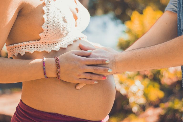 A man putting his hands on a pregnant woman's bump lovingly