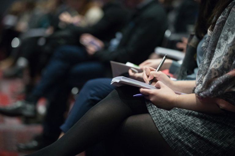 people sat at a conference taking notes