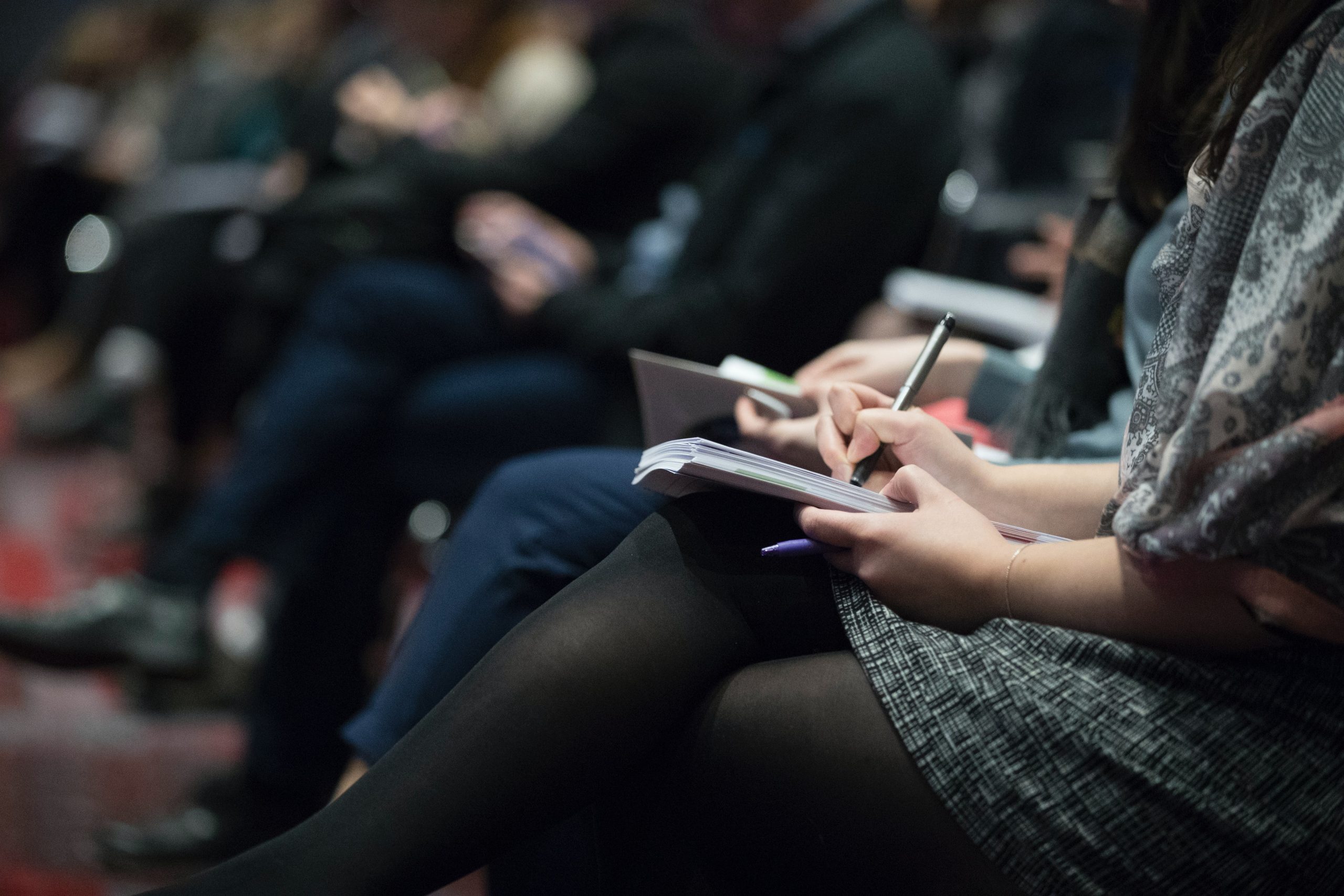 people sat at a conference taking notes