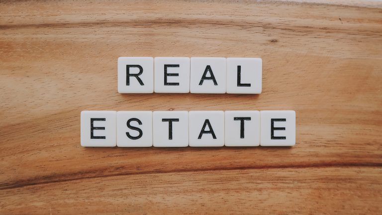 REAL ESTATE spelt out in white letter tiles on a wooden background