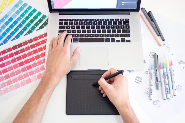 A person sat at a laptop using a drawing pad