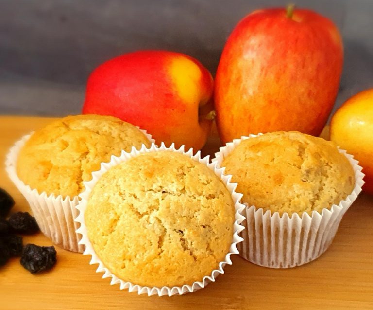 Apple and cherry muffins sat on a wooden chopping board with 3 Jazz apples sat in the background