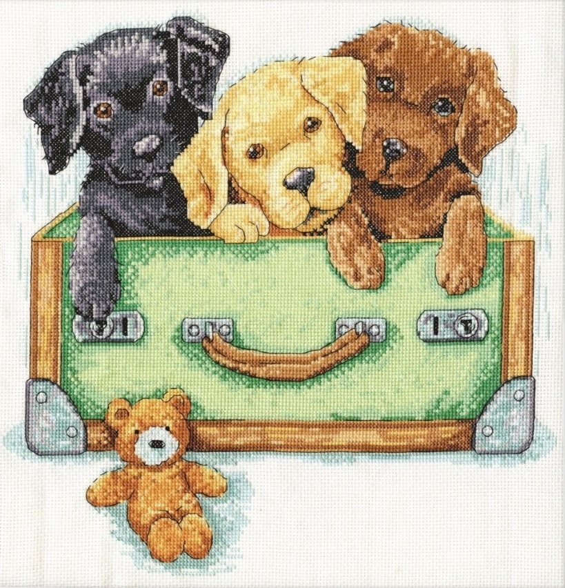 Three puppies—one black, one yellow, and one brown—sit inside a green suitcase, looking forward. In front, a small brown teddy bear lies on the floor, evoking classic toys to keep children occupied. The image features a cross-stitch pattern style.