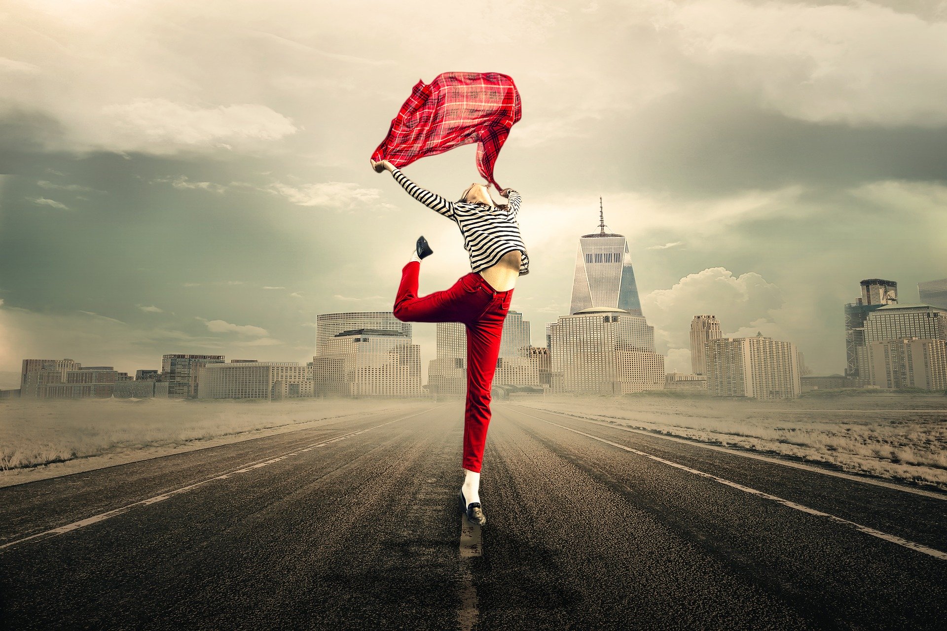 woman wearing read trousers and a grey top dancing