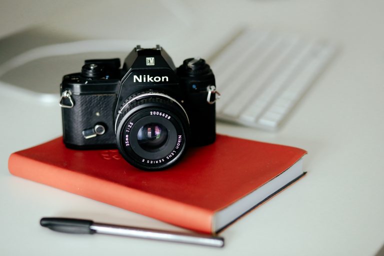 A Nikon camera dslr camera sat on top of a red note book