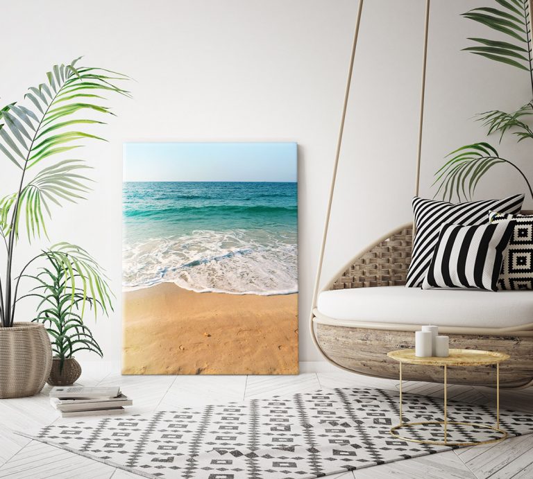 A modern, cosy room perfect for me time, featuring a hanging chair, black and white geometric cushions, leafy plants, and a framed beach photo leaning against the wall on a patterned rug.