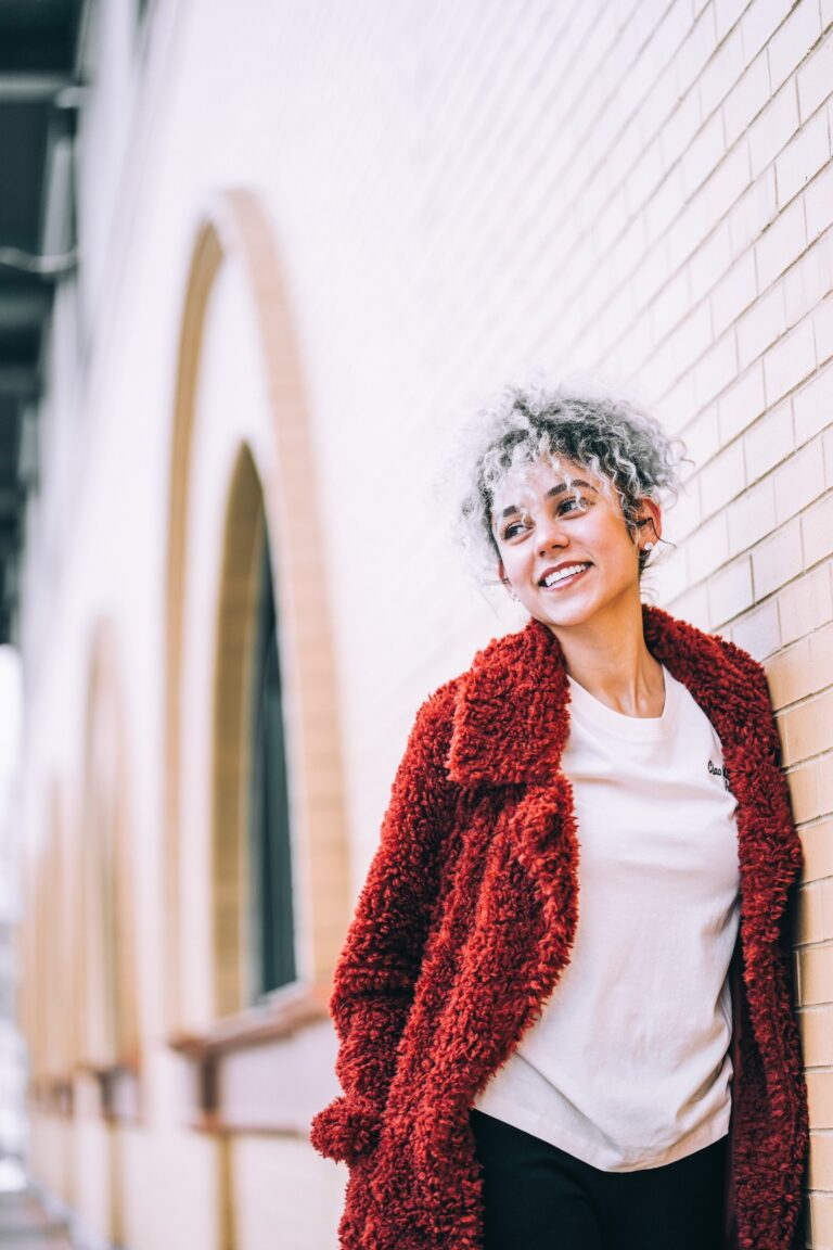 A woman wearing a white tshirt, red cardigan and dark jeans walking in the street
