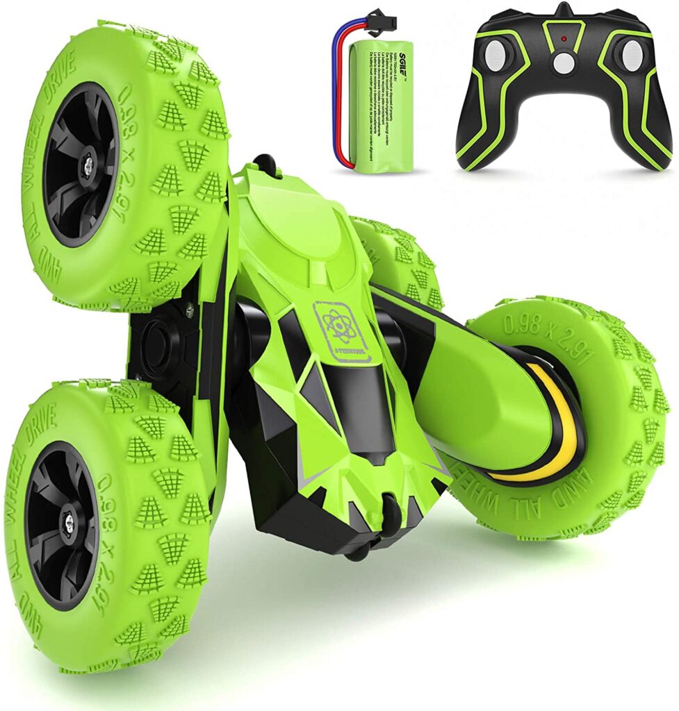 A green and black remote control stunt car with large, rugged tyres is shown next to its matching remote control and a rechargeable battery pack—one of the top Christmas gift ideas for fans of remote control toys.