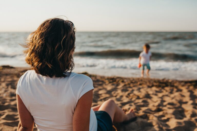 A mum watching her child play on the beach