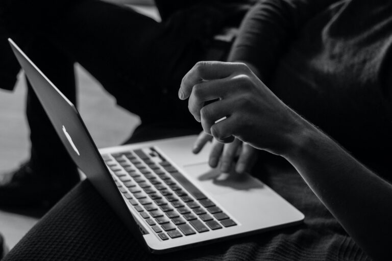 A person's hands typing on a laptop keyboard, with one hand poised above the keys, as if researching "5 Signs Your Child Needs a Tutor." The image is in black and white.
