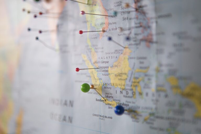 A close-up of a map with several coloured push pins marking locations in Southeast Asia, including Indonesia, Malaysia, and Singapore—perfect for planning your itinerary and considering travel insurance tips. The map is slightly blurred except for the pinned areas.