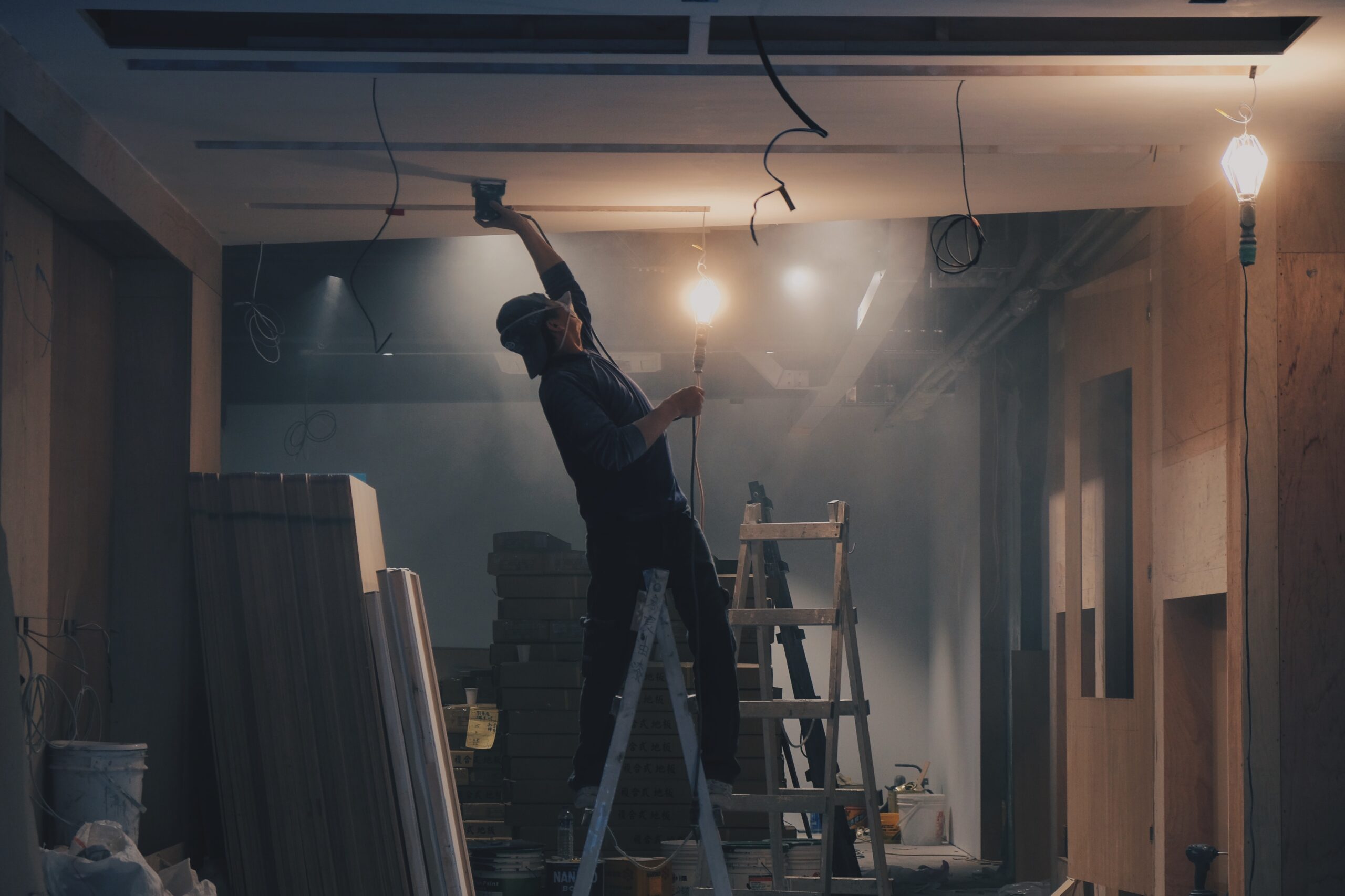 a man stood on a step ladder painting the ceiling