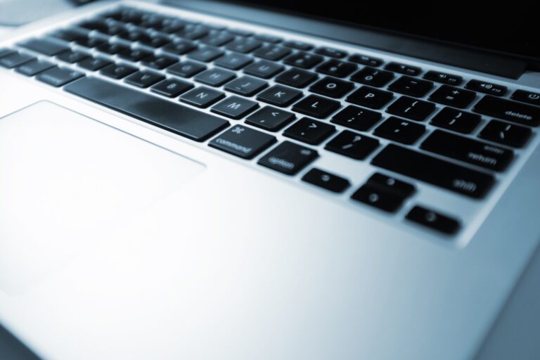 A close-up view of a laptop keyboard and touchpad, showing black keys with white letters on a silver base. The image is slightly angled, focusing on the lower left corner of the keyboard.